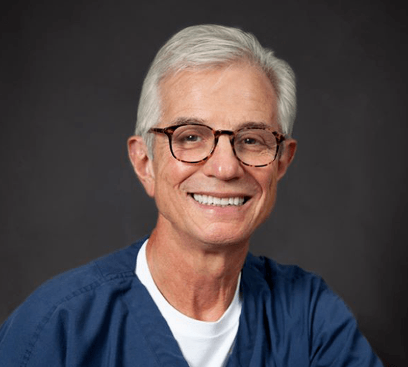 a man wearing glasses and smiling at the camera